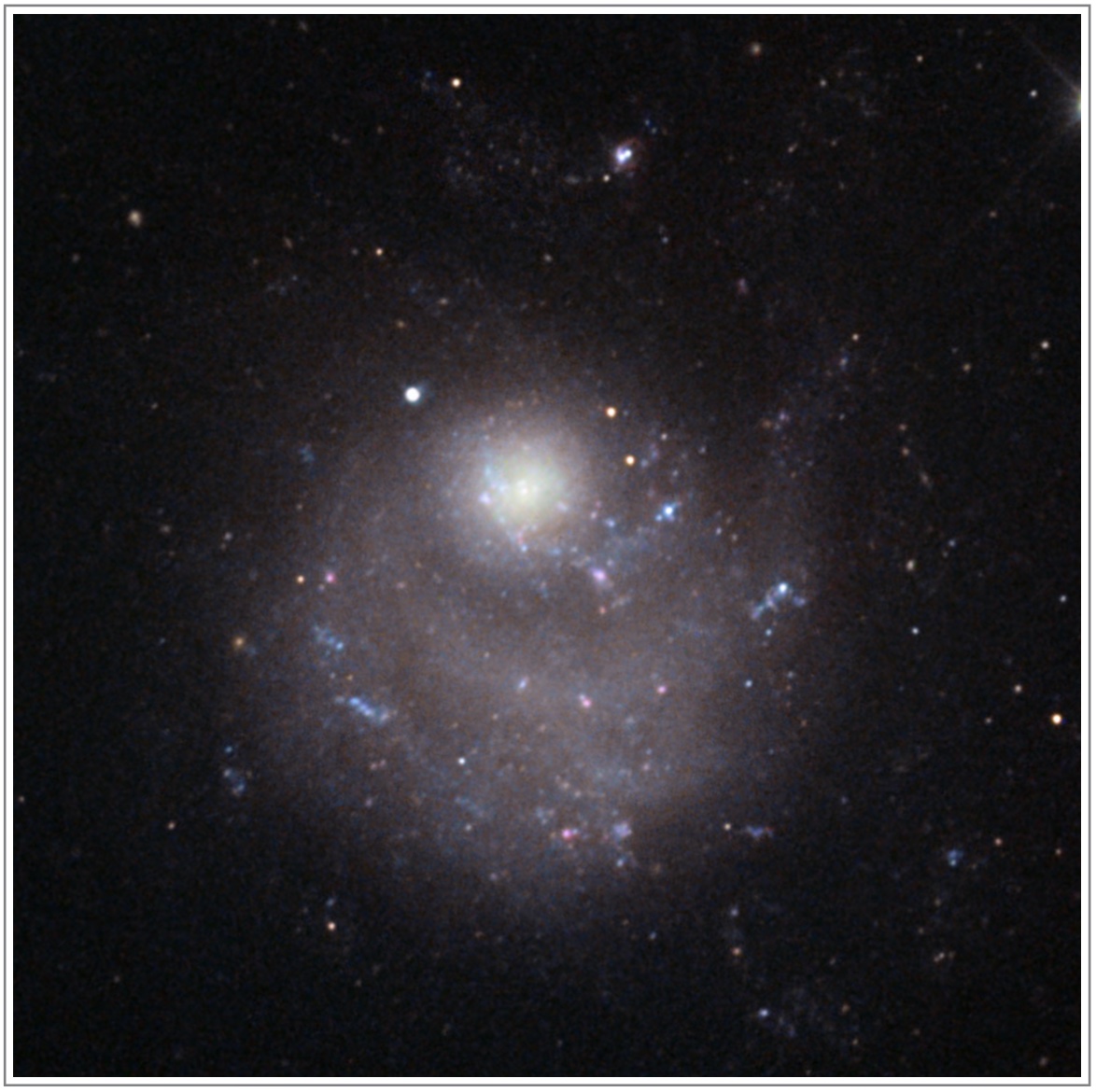 An image showing NGC 5474. There is a bright circular region at the center of the image, with a faint spiral disk offset below it.